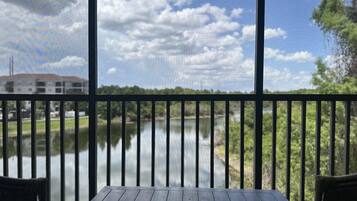 A wooden deck with a view of a calm river and a building across the water.