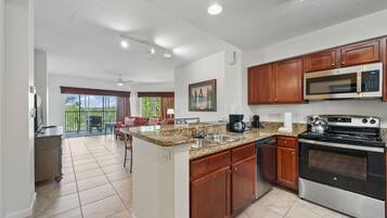 A modern kitchen with granite countertops, stainless steel appliances, and wooden cabinets.