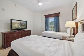 A hotel room with two beds, a television, a desk, and a window with curtains. - 4403 Spacious 2/2 Resort Condo Near Disney (Orlando)