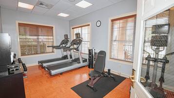 Une salle de sport équipée de tapis de course, d’un banc de musculation et d’une horloge murale.