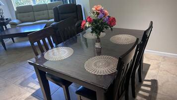 Une table à manger avec quatre chaises, un vase rempli de fleurs et une fenêtre en arrière-plan.