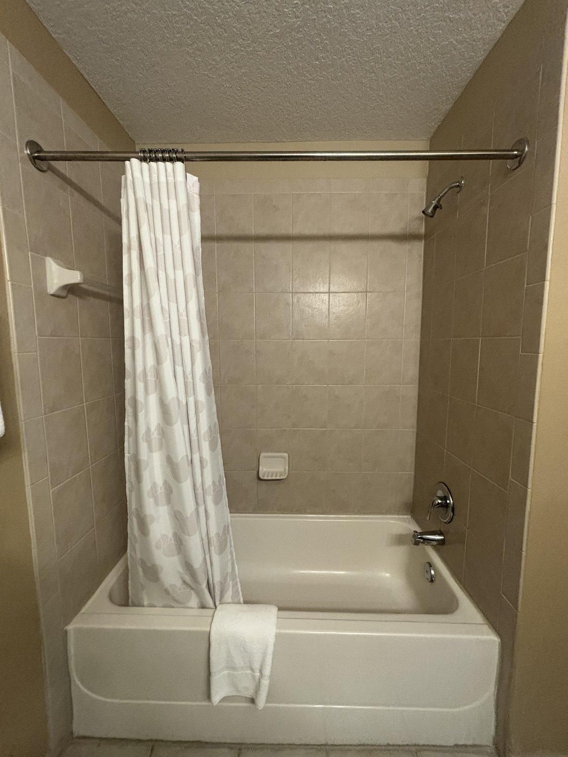 Un baño estándar con una bañera, cortina de ducha y dispensador de jabón para manos.