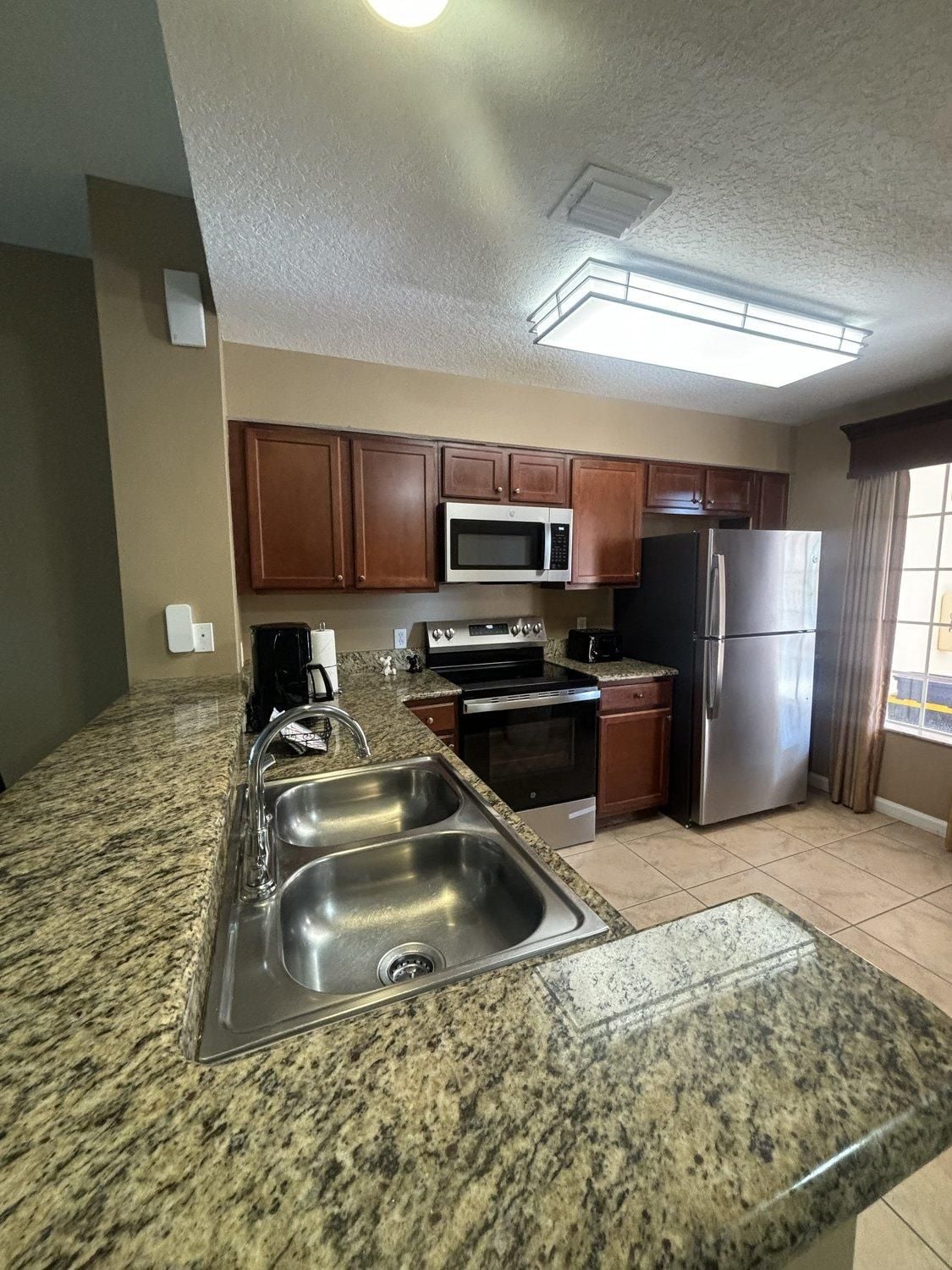 A kitchen with granite countertops, stainless steel appliances, and wooden cabinets.