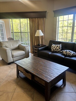 A living room with a sofa, armchair, and a coffee table. - 5303 Spacious 2/2 Resort Condo Near Disney (Orlando)
