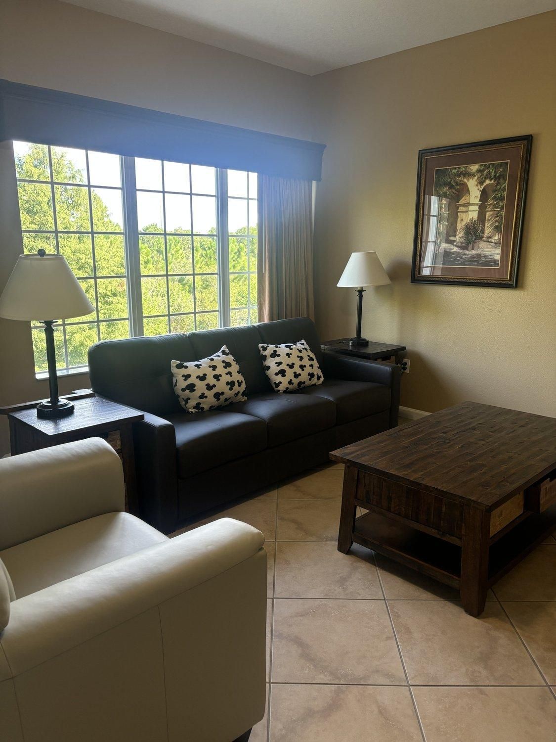A living room with a sofa, a coffee table, a lamp, and a painting on the wall.