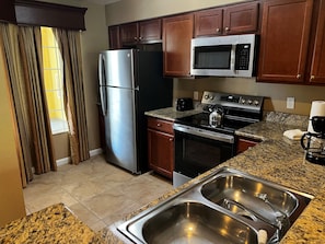 A kitchen with stainless steel appliances, a granite countertop, and a double sink. - 5306 Spacious 2/2 Resort Condo Near Disney (Orlando)