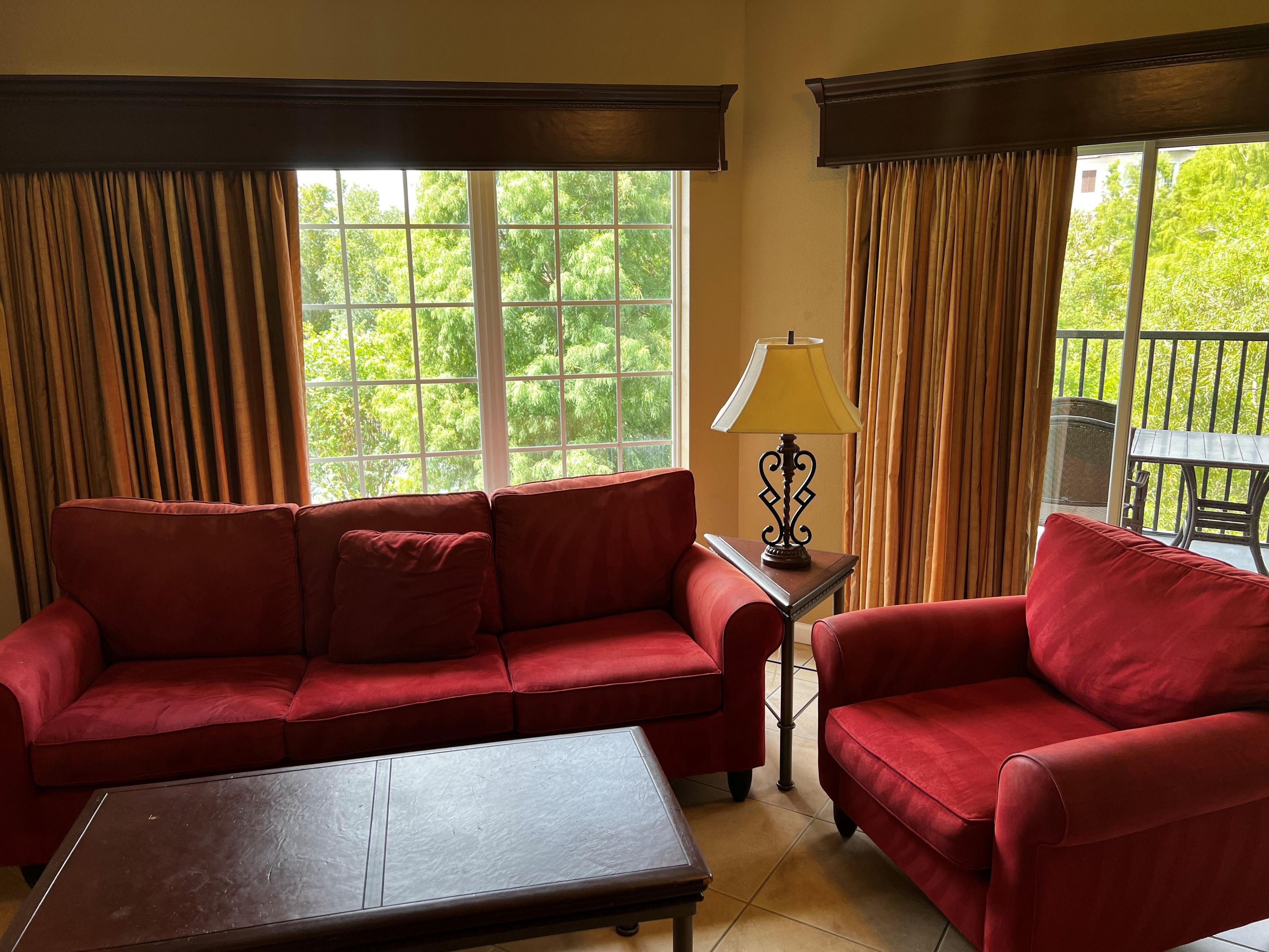 Une pièce avec un canapé rouge, une table basse en bois et une lampe sur une petite table.