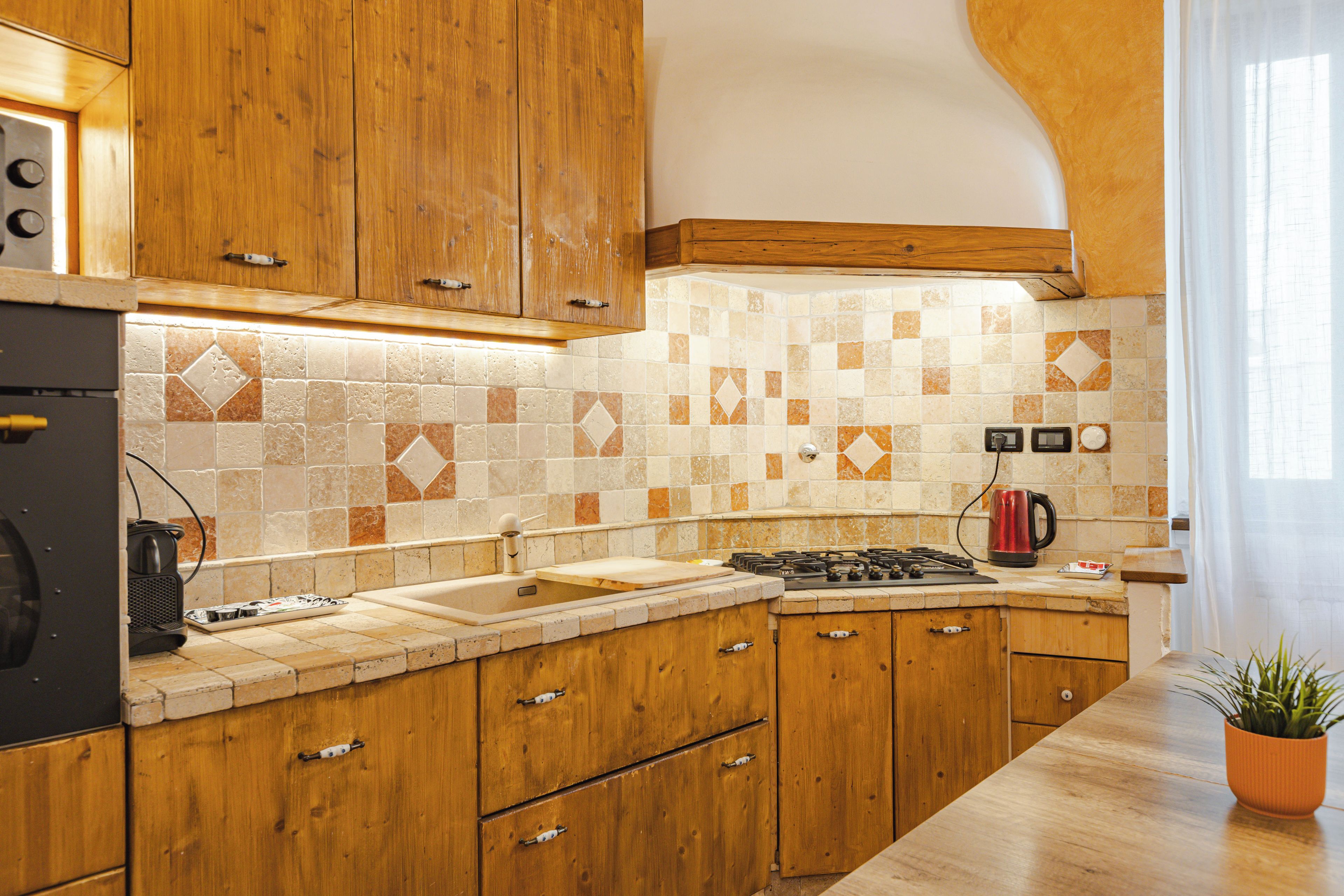 A kitchen with wooden cabinets, a tiled backsplash, and a gas stove.