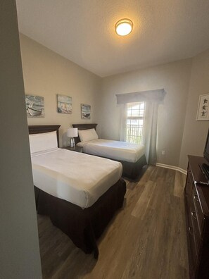 A hotel room with two beds, a window with curtains, a ceiling light, and artwork on the walls. - 5506 Spacious 2/2 Resort Condo Near Disney (Orlando)