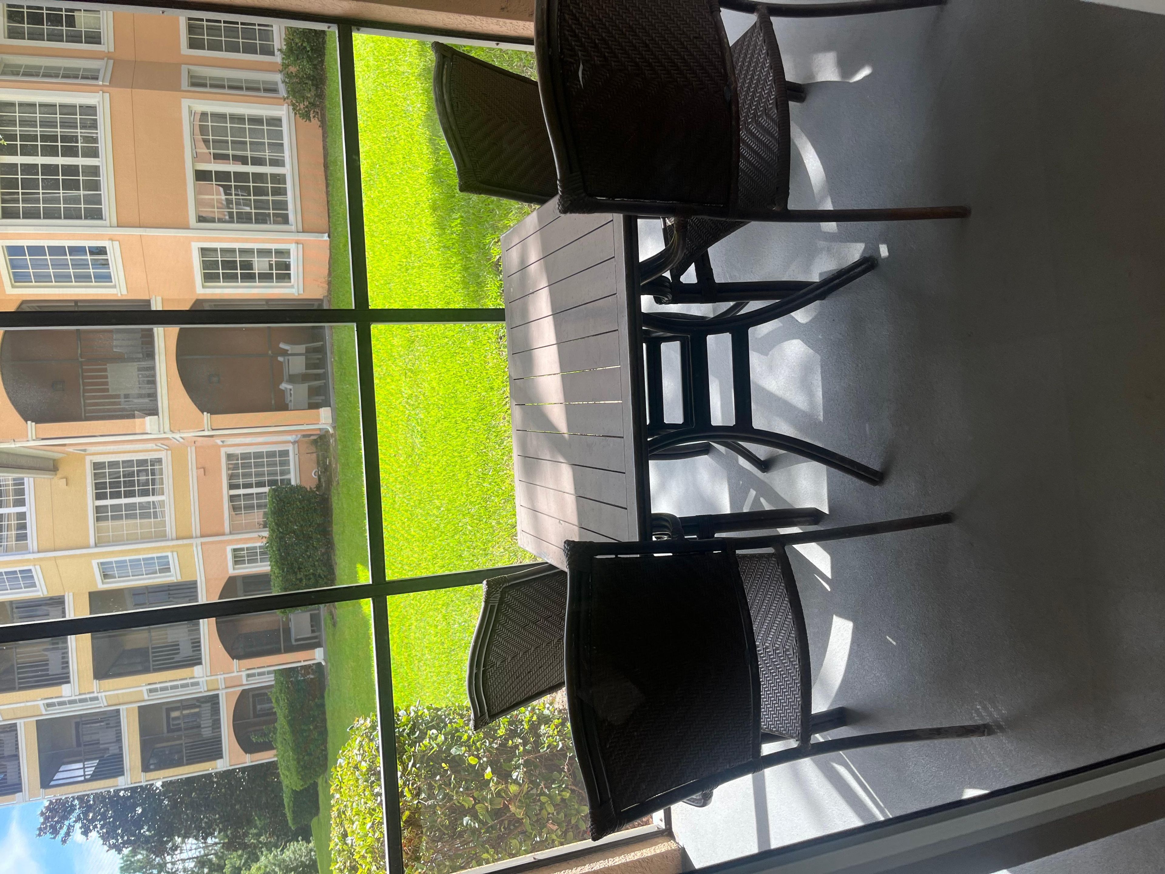 Une pièce avec vue sur un immeuble doté de nombreuses fenêtres et sur une pelouse verdoyante. La pièce contient deux chaises et une table.
