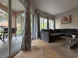 A modern living room with a sofa, coffee table, and a dining area with chairs and a table.