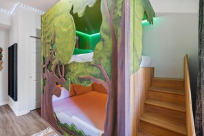 A bedroom with a tree-themed canopy bed, a staircase, and a wall-mounted TV. - 6306 Stunning 2/2 Resort Condo Near Disney (Orlando)