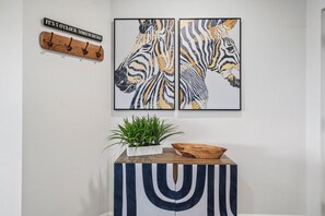 A wall with two framed zebra prints and a wooden coat rack with a sign. - 6306 Stunning 2/2 Resort Condo Near Disney (Orlando)