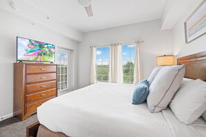 A bedroom with a bed, a TV on a wooden dresser, and a window with blinds. - 6406 Spacious 2/2 Resort Condo Near Disney (Orlando)