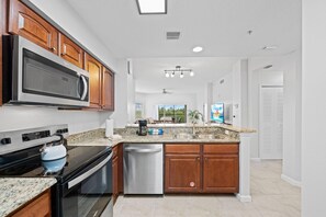 Una cocina moderna con encimeras de granito, electrodomésticos de acero inoxidable y armarios de madera.