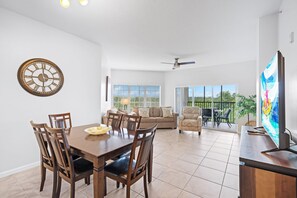 A spacious living area with a dining table, chairs, a sofa, and a television. - 6406 Spacious 2/2 Resort Condo Near Disney (Orlando)