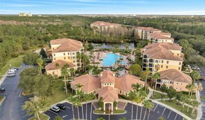 Un resort con diversi edifici, una piscina centrale e un'area parcheggio.