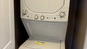 A front-loading washing machine with control knobs and a detergent packet on the door.
