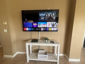 Un televisor de pantalla plana montado en la pared, con un mueble de entretenimiento blanco debajo.