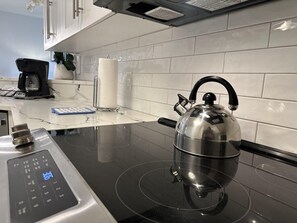 Ett modernt kök med en induktionshäll, en vattenkokare och en kaffebryggare.