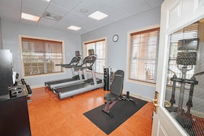 A gym with treadmills, a weight bench, and a wall clock. - 1101 Spacious 3/2 Resort Condo Near Disney (Orlando)