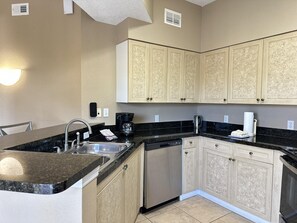 A kitchen with a built-in dishwasher, a coffee maker, and a stove. - 1302 Spacious 3/2 Resort Condo Near Disney (Orlando)