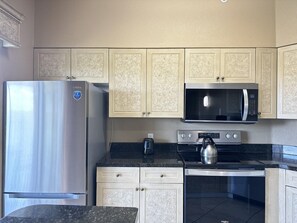 A kitchen with a stainless steel refrigerator, a microwave, a kettle, and a dishwasher. - 1407 Spacious 3/2 Resort Condo Near Disney (Orlando)