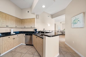 A modern kitchen with a central island, built-in cabinets, and a dining area in the background.