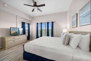 A bedroom with a bed, a dresser, a television, and a ceiling fan.