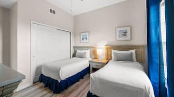 Ein Hotelzimmer mit zwei Betten, einem Nachttisch mit Lampe, einer Tür und zwei gerahmten Bildern an der Wand.