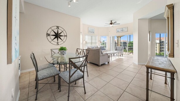 A spacious living area with a dining table, chairs, and a sofa. There is a large window providing a view of the outdoors. - 1507 Spacious 3/2 Resort Condo Near Disney (Orlando)