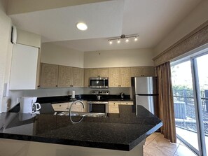 Cocina moderna con una isla central, electrodomésticos de acero inoxidable y un amplio ventanal con vistas.