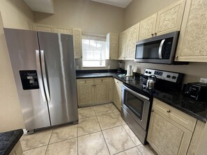 A kitchen with a stainless steel refrigerator, a microwave, an oven, and a toaster. - 2201 Spacious 3/2 Resort Condo Near Disney (Orlando)