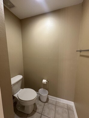 A small bathroom with a toilet, a trash can, and a toilet paper holder on the wall. - 2201 Spacious 3/2 Resort Condo Near Disney (Orlando)