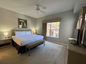 A bedroom with a bed, bedside lamps, a ceiling fan, a window with curtains, and a television on a dresser. - 2202 Spacious 3/2 Resort Condo Near Disney (Orlando)