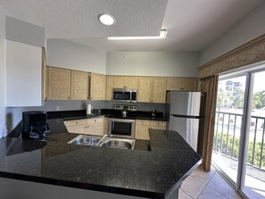 A modern kitchen with a central island, stainless steel appliances, and a view to the outside. - 2202 Spacious 3/2 Resort Condo Near Disney (Orlando)