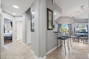 A modern interior with a dining area, a kitchen, and a hallway leading to a bedroom. - 2208 Spacious 3/2 Resort Condo Near Disney (Orlando)
