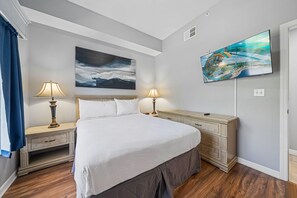 A bedroom with a bed, two bedside tables with lamps, a dresser, a painting above the bed, and a television on the wall. - 2208 Spacious 3/2 Resort Condo Near Disney (Orlando)