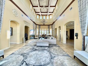 A spacious living room with a marble-patterned rug, a large sofa, and a chandelier. - 2208 Spacious 3/2 Resort Condo Near Disney (Orlando)