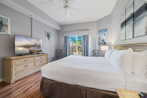Une chambre d’hôtel avec un grand lit, une télévision, une commode et un ventilateur de plafond.