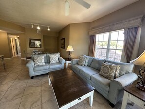 A living room with a sofa set, a coffee table, and a dining area with chairs. - 2307 Spacious 3/2 Resort Condo Near Disney (Orlando)