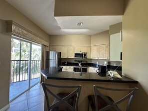 A kitchen with a central island, stainless steel appliances, and a view to the outside. - 2307 Spacious 3/2 Resort Condo Near Disney (Orlando)