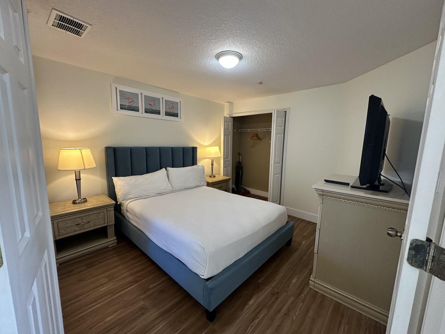 A bedroom with a bed, bedside lamps, a wardrobe, and a television.