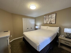 A hotel room with a bed, a desk, a lamp, a phone, and a door. - 2407 Spacious 3/2 Resort Condo Near Disney (Orlando)