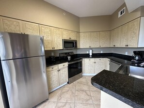 A kitchen with stainless steel appliances, beige cabinetry, and a granite countertop. - 2407 Spacious 3/2 Resort Condo Near Disney (Orlando)
