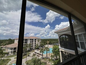A view of a hotel with a pool, outdoor seating, and a landscaped area. - 2507 Spacious 3/2 Resort Condo Near Disney (Orlando)
