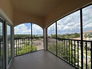 A balcony with a view of a residential area, a clear sky, and a building with a red roof in the distance. - 2507 Spacious 3/2 Resort Condo Near Disney (Orlando)