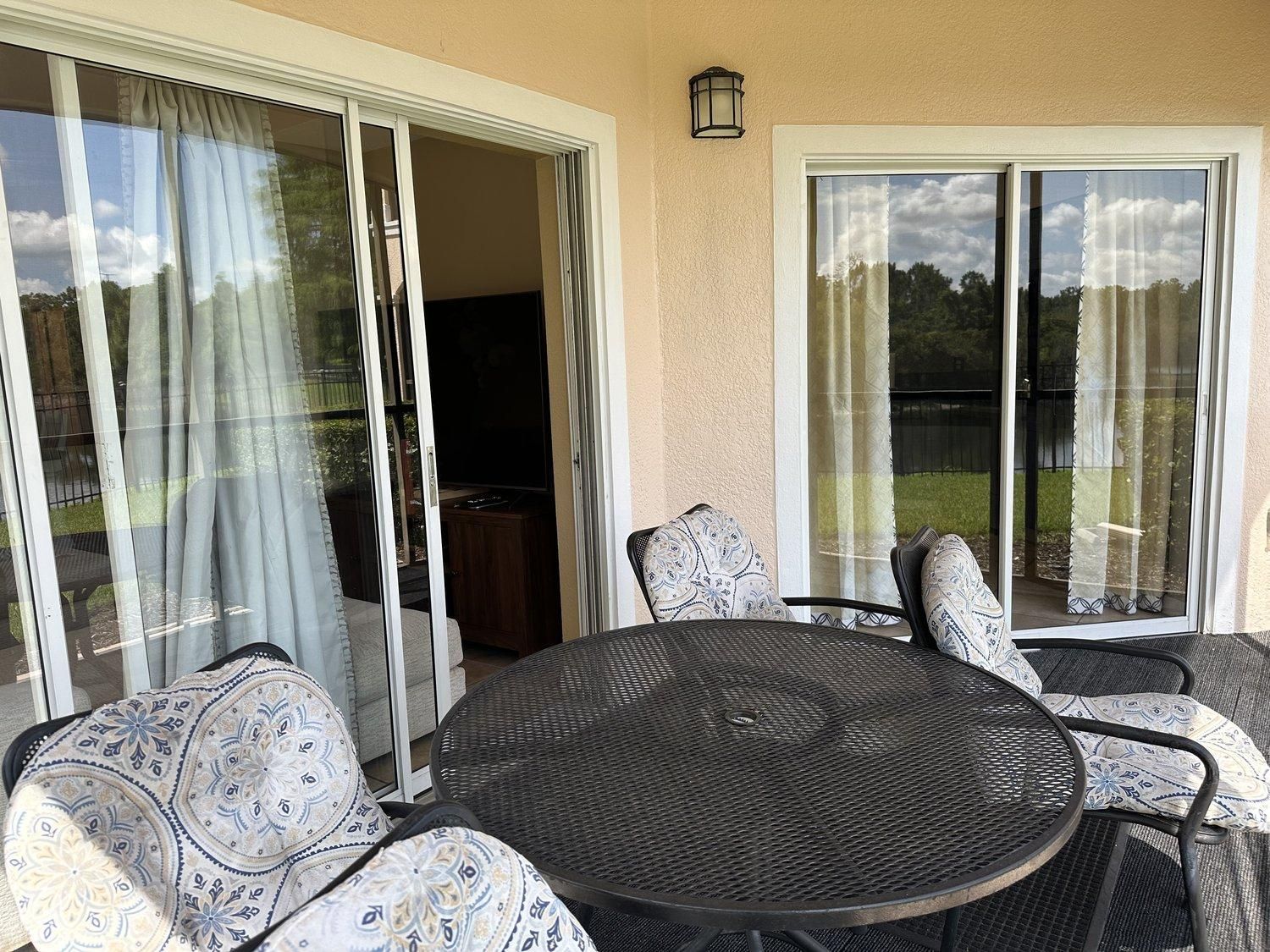 Une terrasse avec une table ronde et des chaises, un téléviseur et une porte-fenêtre coulissante.