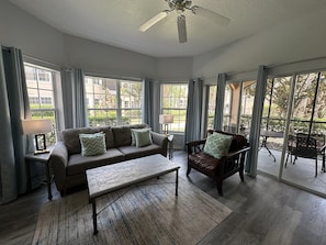 A spacious living room with a sofa, armchair, and a coffee table. There are large windows providing natural light and views of the outdoors. - 3108 Spacious 3/2 Resort Condo Near Disney (Orlando)