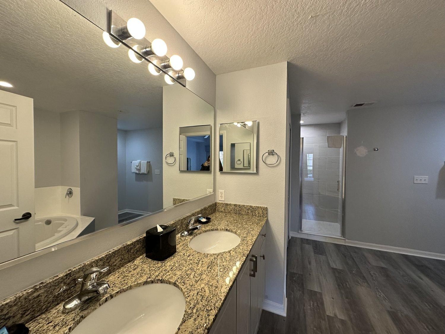 A bathroom with two sinks, a large mirror, and a vanity with a granite countertop.